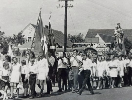 Procesja z figurami świętych podczas odpustu św. Rocha w Dobrzeniu Wielkim — pielgrzymi, sztandary i orkiestra w drodze do drewnianego kościoła.