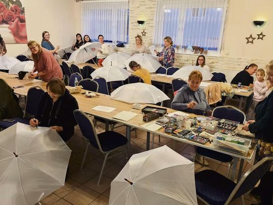 Warsztaty artystyczne w klubie wiejskim w Dębiu, podczas których mieszkańcy malowali tradycyjne opolskie wzory kwiatowe i kolorowe motywy na parasolkach.