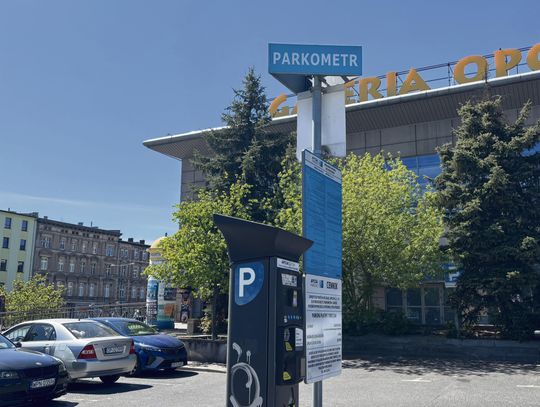 Inkasent wystawiający mandat na parkingu przed marketem w Opolu, obok parkometru