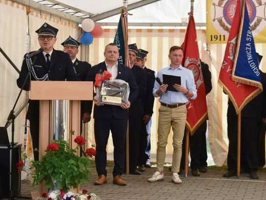 Strażacy OSP Krzyżowa Dolina podczas obchodów 115‑lecia jednostki, z orkiestrą i mieszkańcami w przemarszu