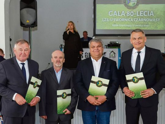 Uczestnicy gali 80‑lecia LZS Swornica Czarnowąsy podczas uroczystości z historycznymi fotografiami klubu.