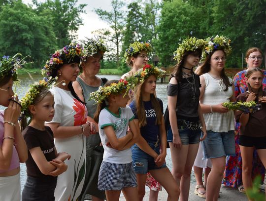 Uczestnicy Nocy Świętojańskiej w Chróścinie puszczający wianki na wodę podczas wieczornego wydarzenia.