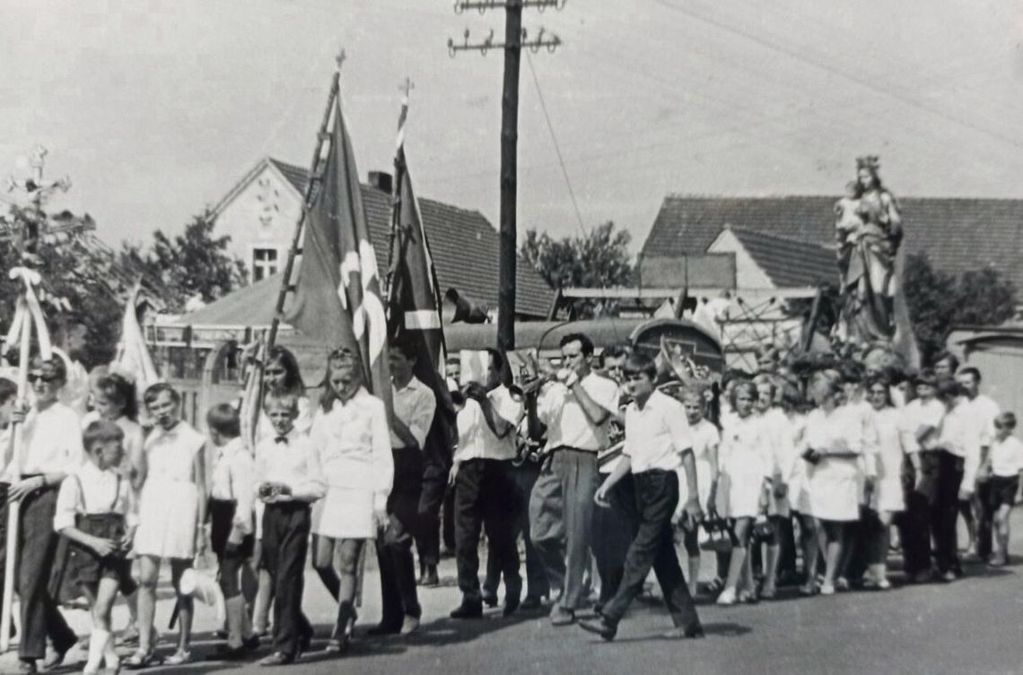 Procesja z figurami świętych podczas odpustu św. Rocha w Dobrzeniu Wielkim — pielgrzymi, sztandary i orkiestra w drodze do drewnianego kościoła.