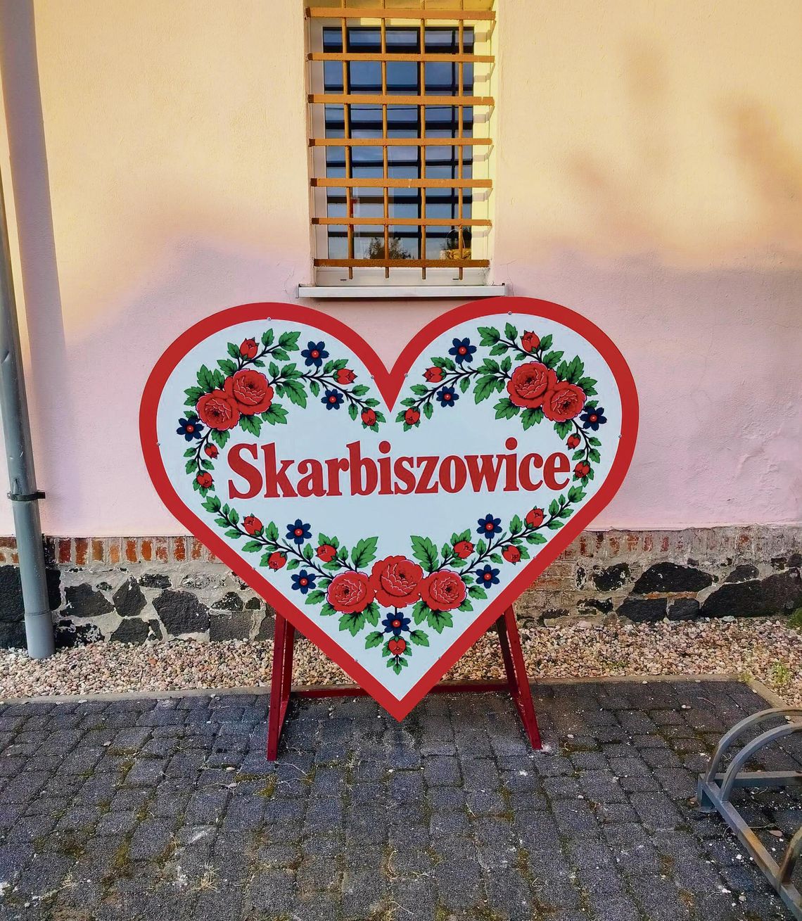 Serce na nakrętki w Skarbiszowicach w gminie Tułowice z nazwą miejscowości i dekoracyjnym wzorem inspirowanym strojami ludowymi.
