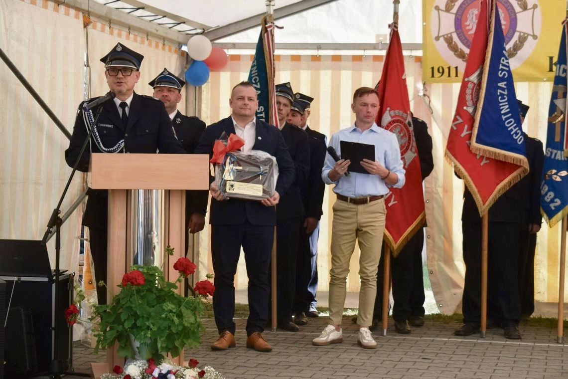 Strażacy OSP Krzyżowa Dolina podczas obchodów 115‑lecia jednostki, z orkiestrą i mieszkańcami w przemarszu