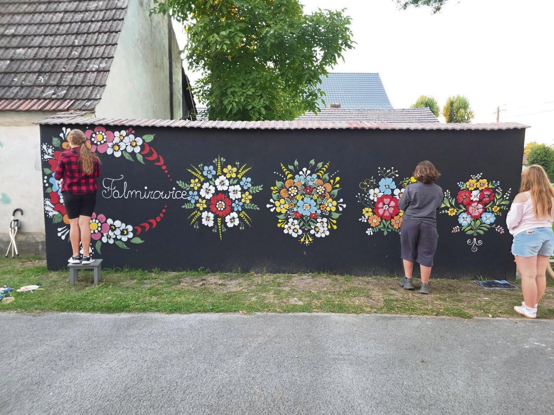 Wyjątkowy mural w Falmirowicach. Cała wieś malowała opolskie wzory — efekt zachwyca Mieszkańcy Falmirowic malują mural z opolskimi wzorami, tworząc kolorowe kwiaty na ścianie budynku.